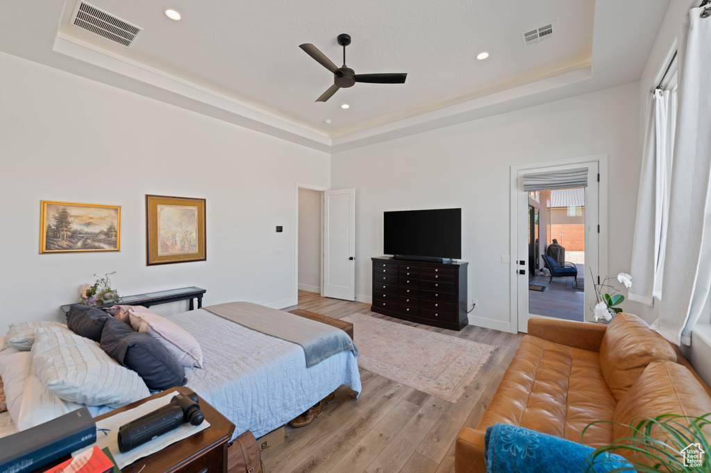 Bedroom with a raised ceiling, light wood-type flooring, a ceiling fan, recessed lighting, and baseboards