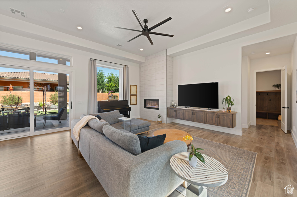Living room featuring a ceiling fan, wood finished floors, a tiled fireplace, recessed lighting, and baseboards