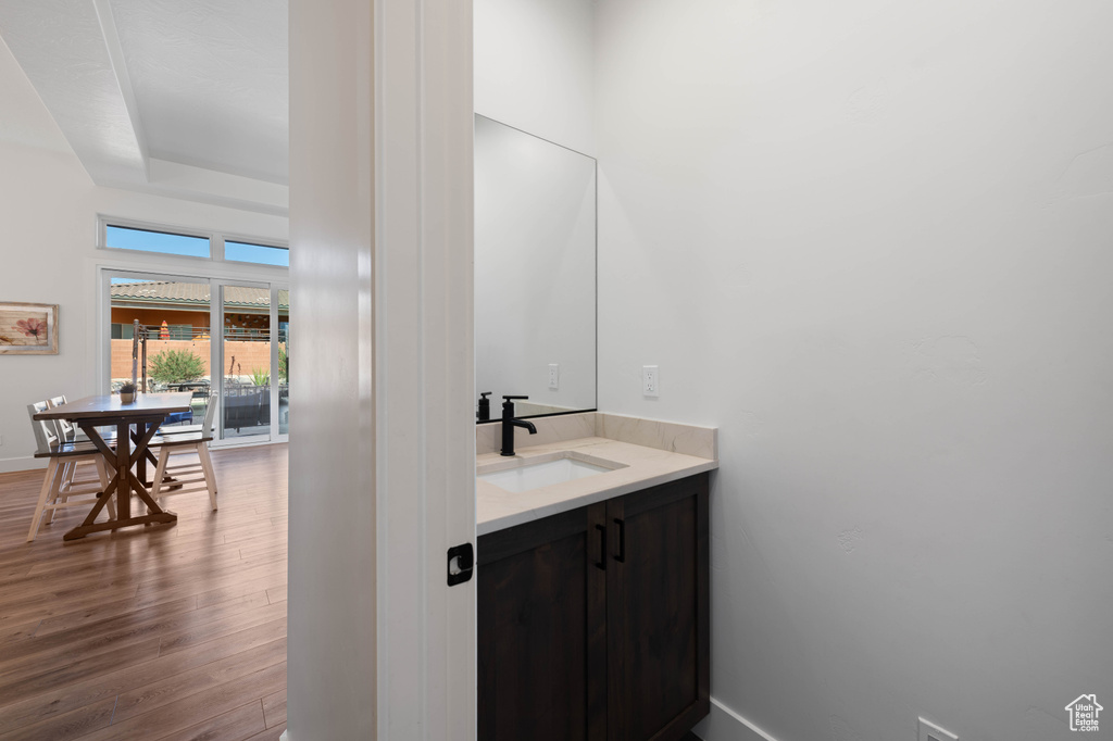 Bathroom with wood finished floors, vanity, baseboards, and a tray ceiling