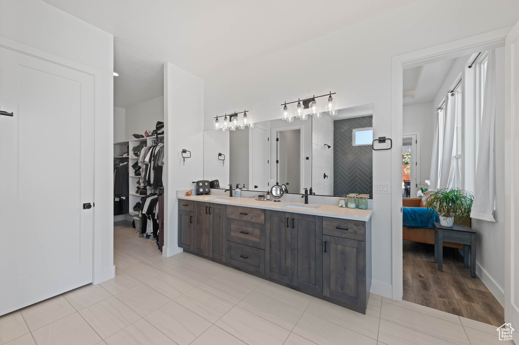 Ensuite bathroom with double vanity, a walk in shower, a walk in closet, and tile patterned flooring
