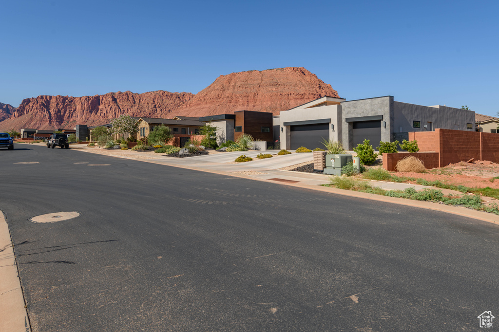 View of front of house featuring a mountain view, concrete driveway, a garage, and stucco siding