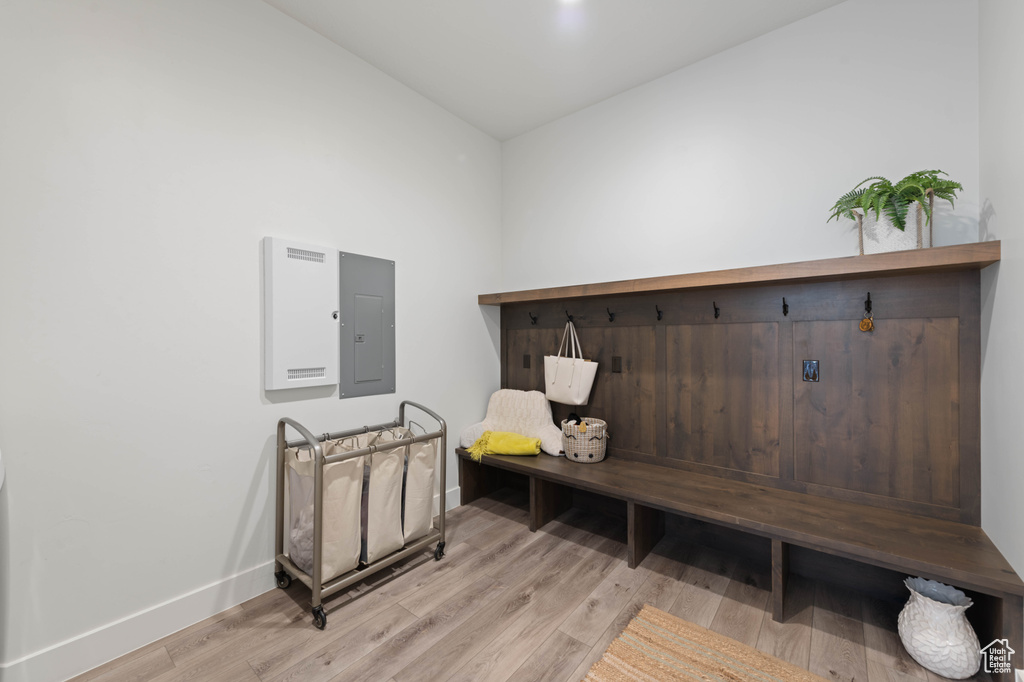 Mudroom with electric panel, baseboards, and light wood-style floors