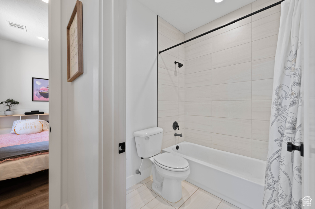 Ensuite bathroom featuring shower / bath combo, toilet, baseboards, tile patterned floors, and recessed lighting