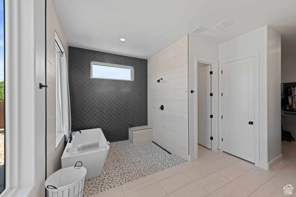 Bathroom with walk in shower, a closet, a freestanding bath, and tile patterned floors