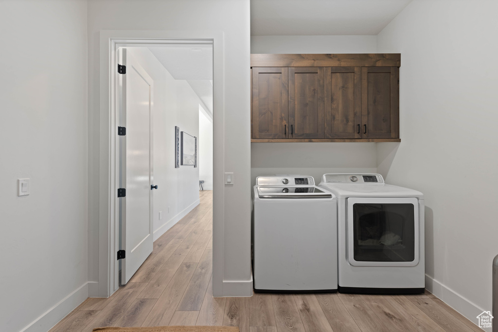 Laundry room featuring cabinet space, washing machine and dryer, light wood finished floors, and baseboards