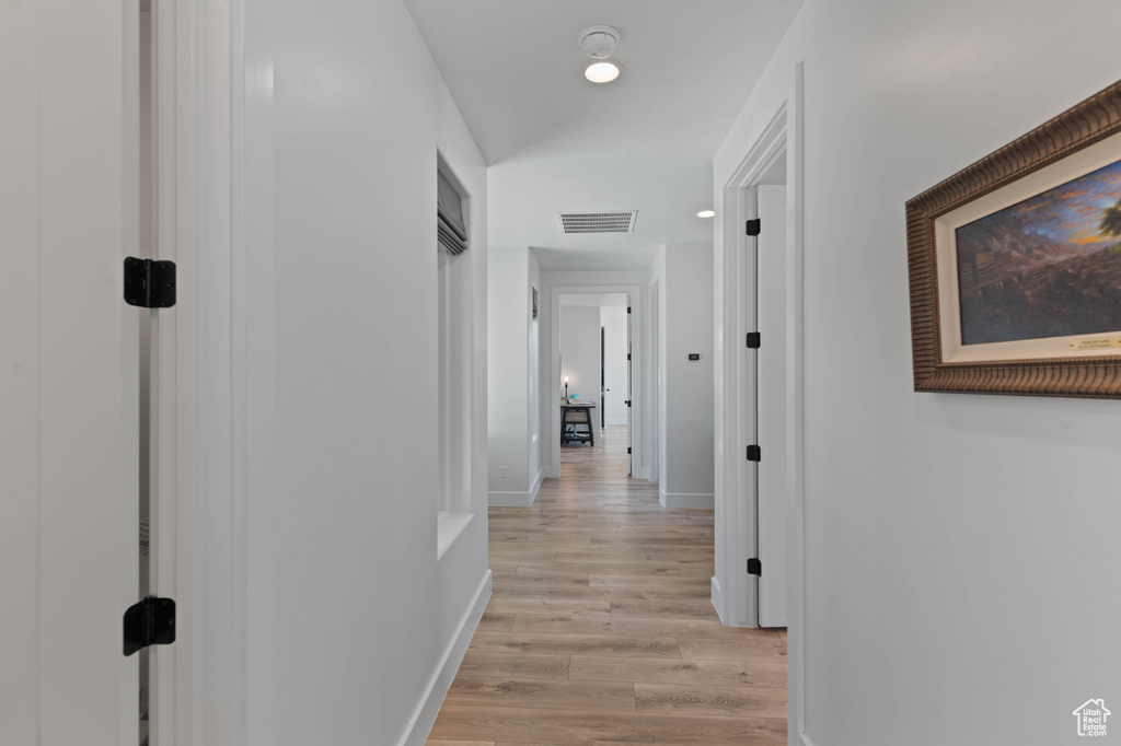 Corridor with light wood finished floors, baseboards, and recessed lighting