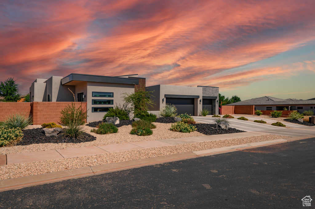Contemporary home featuring stucco siding, a garage, and driveway