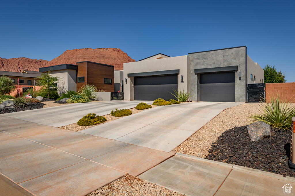 Contemporary house with stucco siding, driveway, an attached garage, and a mountain view