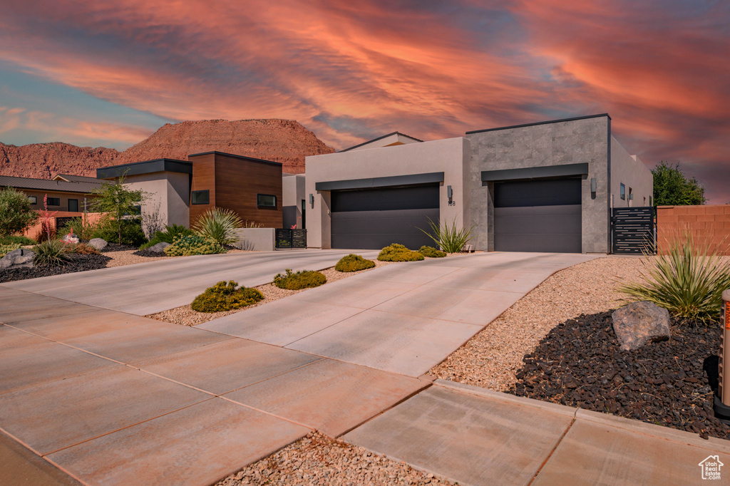 Modern home with stucco siding, concrete driveway, a mountain view, and an attached garage