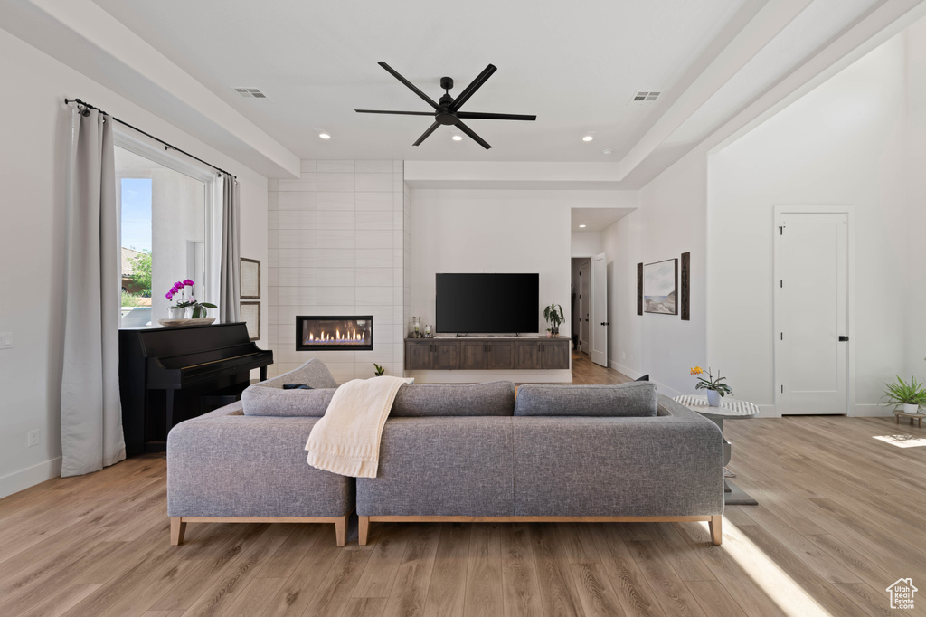 Living room with ceiling fan, light wood-type flooring, baseboards, a fireplace, and recessed lighting