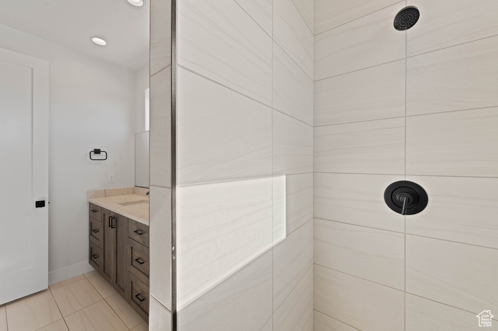 Full bath with a tile shower, vanity, baseboards, and tile patterned floors