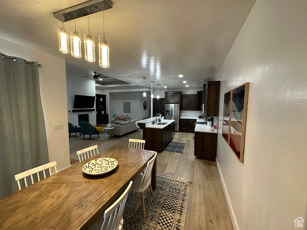 Dining area featuring light wood-type flooring, baseboards, a fireplace, a ceiling fan, and recessed lighting