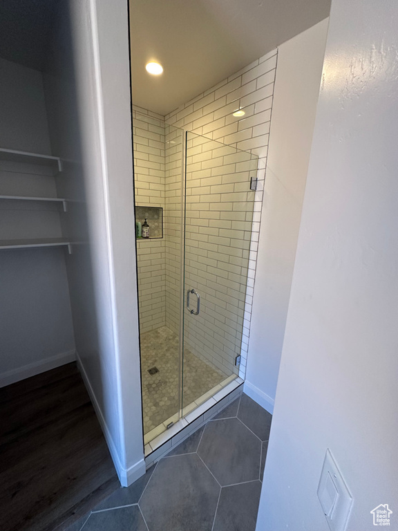 Full bath with a shower stall, tile patterned floors, and baseboards
