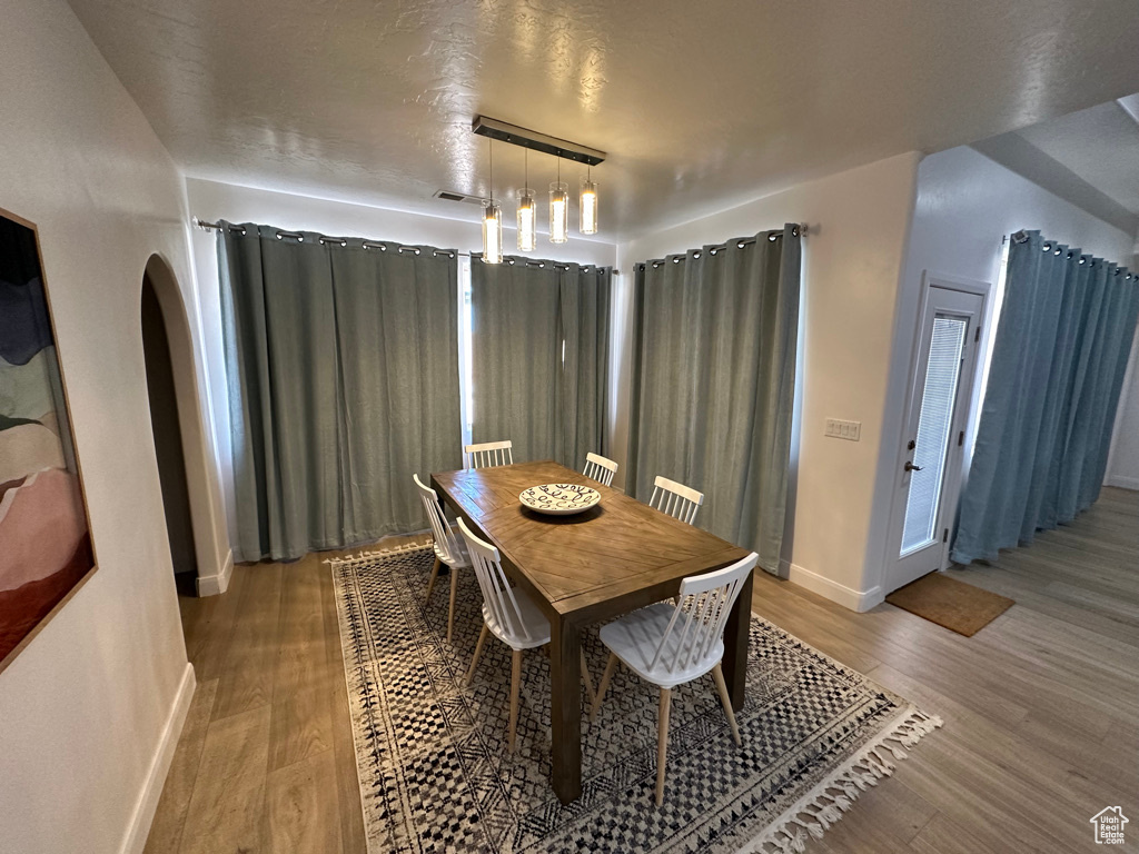 Dining room with arched walkways, light wood-type flooring, and baseboards