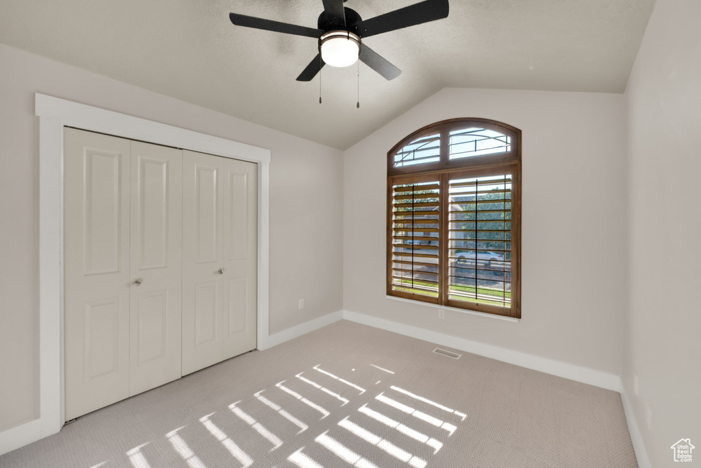 Unfurnished bedroom with carpet flooring, lofted ceiling, baseboards, and a closet