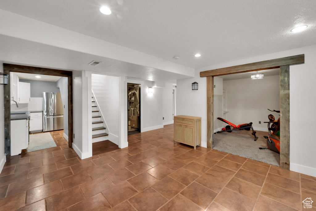 Finished basement with freestanding refrigerator, stairs, recessed lighting, and baseboards