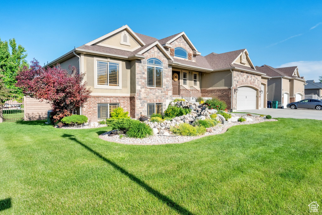 View of front of property featuring stone siding, stucco siding, concrete driveway, and a front yard