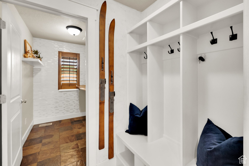 Mudroom with wallpapered walls, baseboards, and stone finish floors