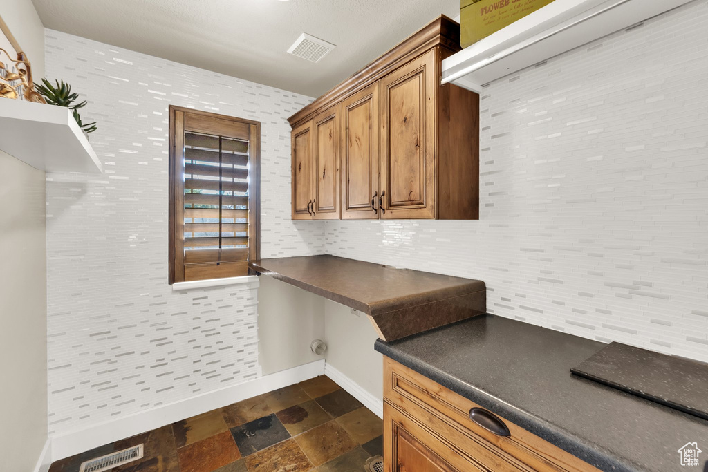 Washroom with baseboards and dark stone finish floors