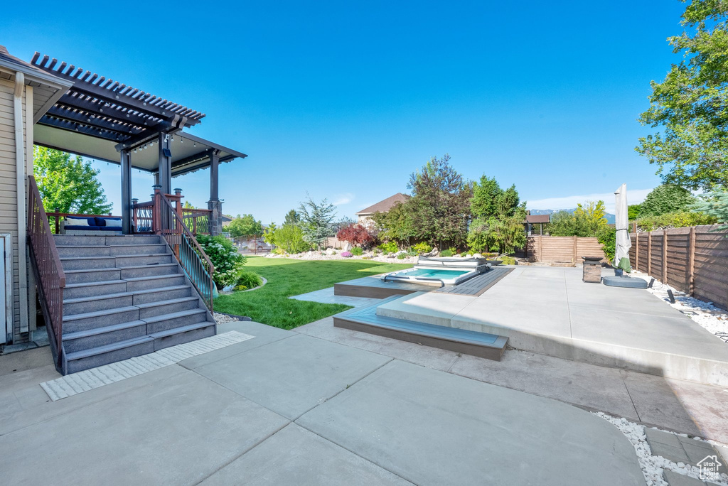 View of patio with an in-ground hot tub and a pergola