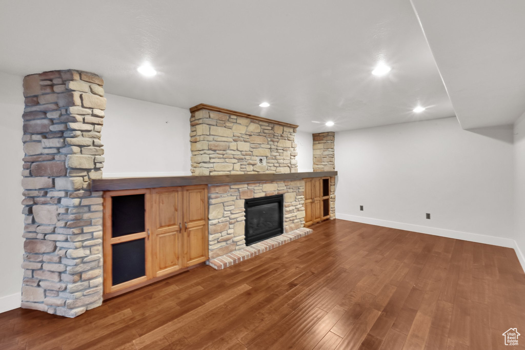 Unfurnished living room featuring a fireplace, baseboards, wood finished floors, and recessed lighting