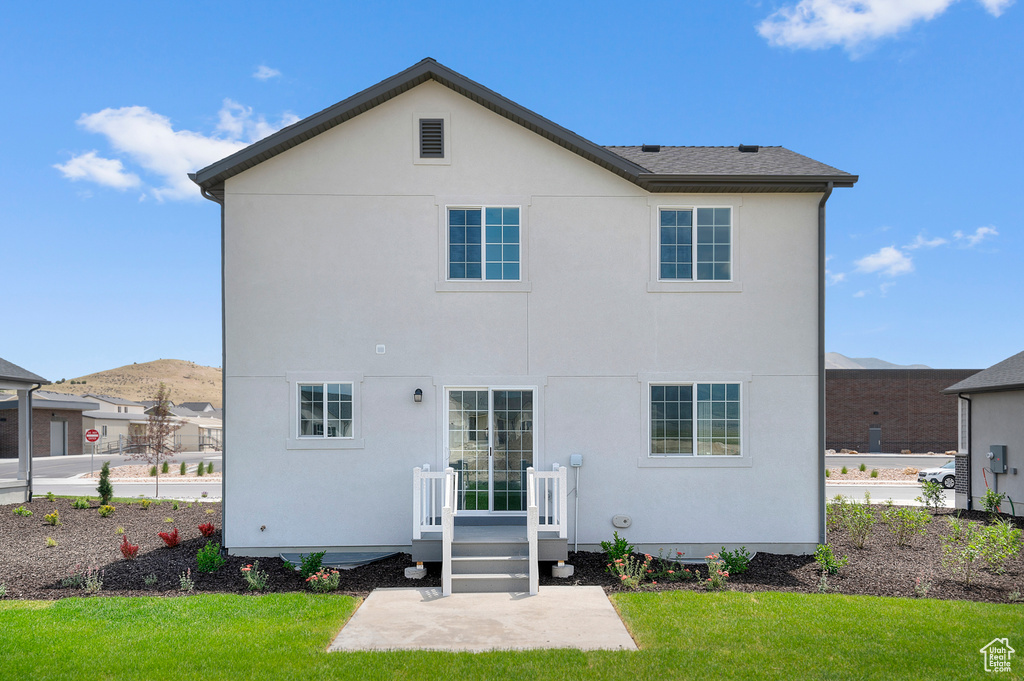 Back of house with a yard, stucco siding, a mountain view, and a patio area