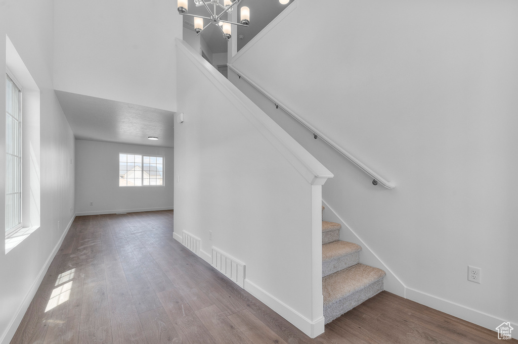 Stairs featuring baseboards, wood finished floors, and a chandelier