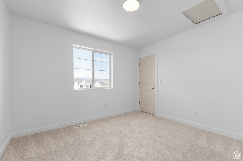 Unfurnished room featuring carpet flooring, baseboards, and attic access