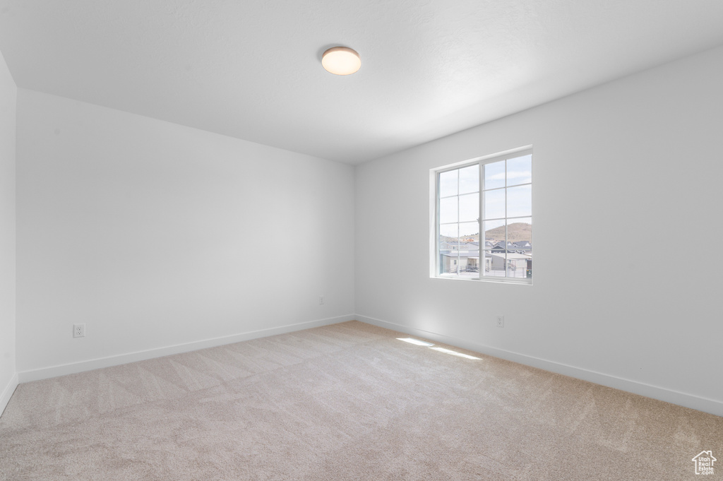 Carpeted spare room featuring baseboards