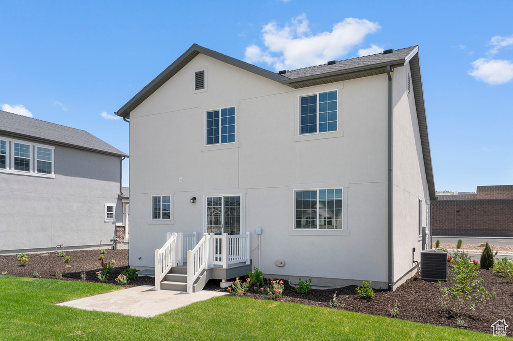 Rear view of house with central AC, stucco siding, a yard, and a patio area
