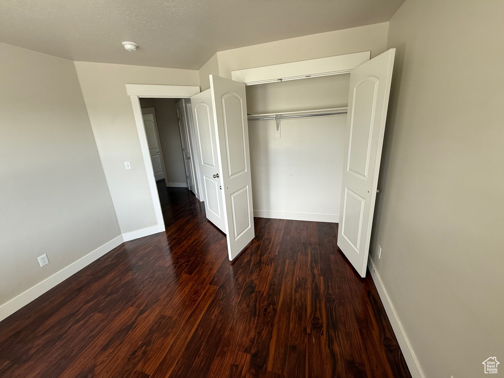 Unfurnished bedroom featuring baseboards, wood finished floors, and a closet