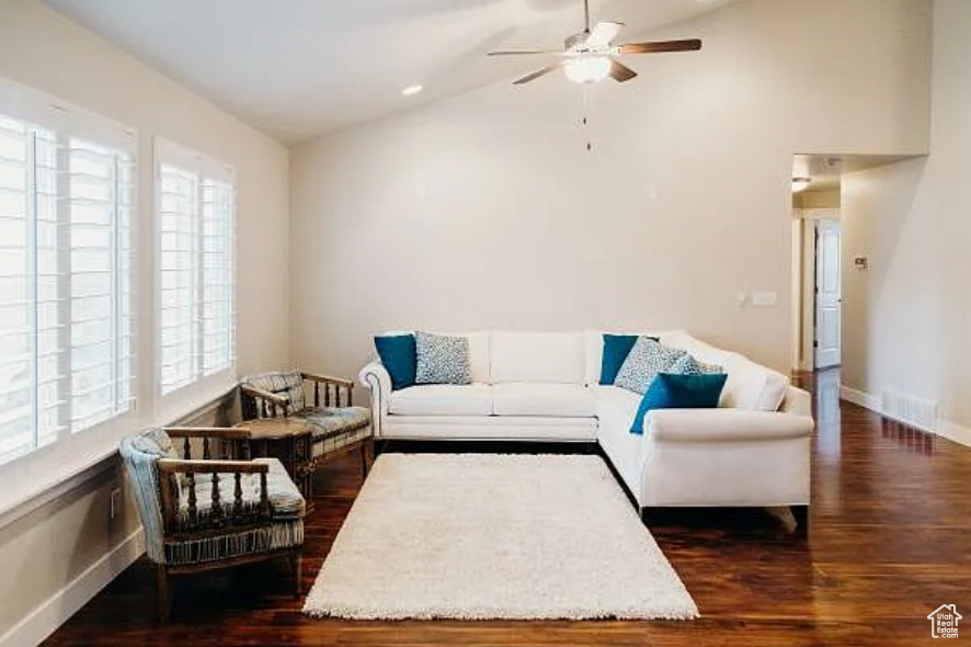 Living room with wood finished floors, a ceiling fan, vaulted ceiling, and baseboards