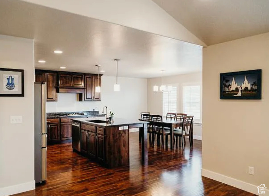 Kitchen featuring dishwasher, a sink, dark countertops, baseboards, and dark wood-style flooring