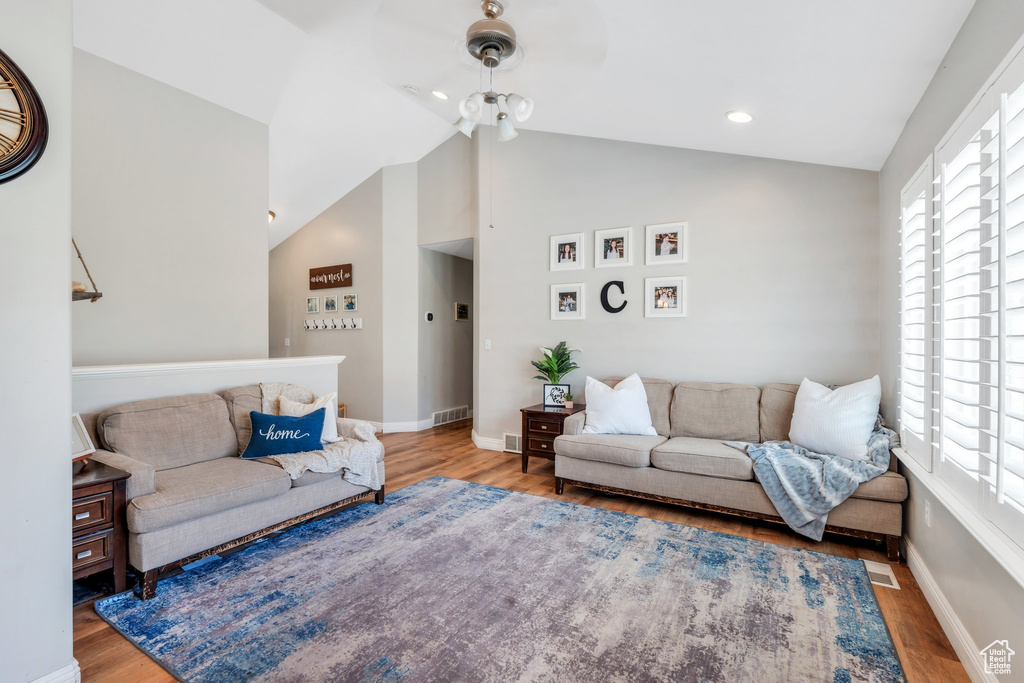 Living area with wood finished floors, lofted ceiling, baseboards, and recessed lighting