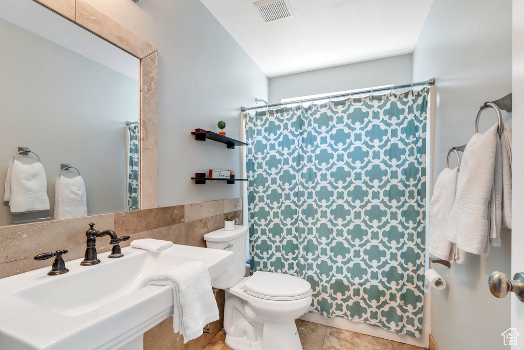 Full bathroom featuring toilet, a sink, tile walls, and curtained shower