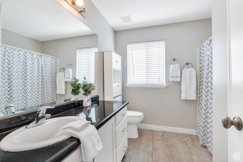 Full bathroom with vanity, toilet, baseboards, and curtained shower