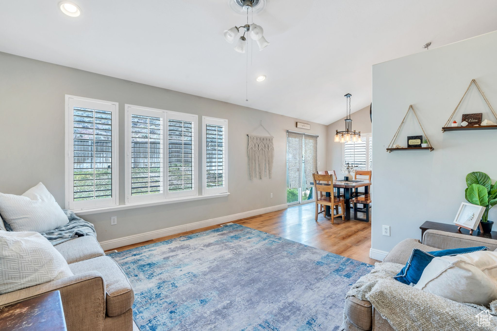 Living room featuring a chandelier, wood finished floors, baseboards, recessed lighting, and vaulted ceiling