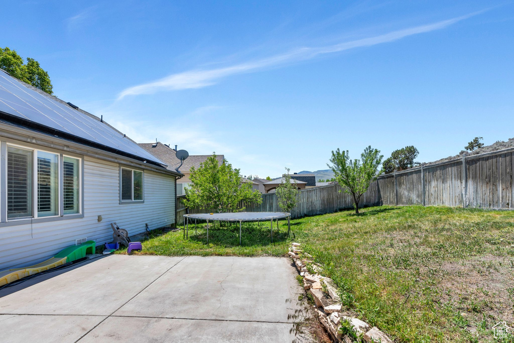 View of yard featuring a trampoline and a patio
