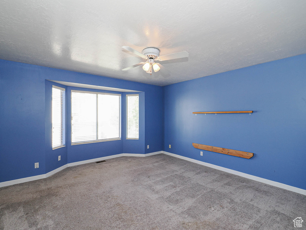 Empty room featuring a ceiling fan, carpet floors, and baseboards