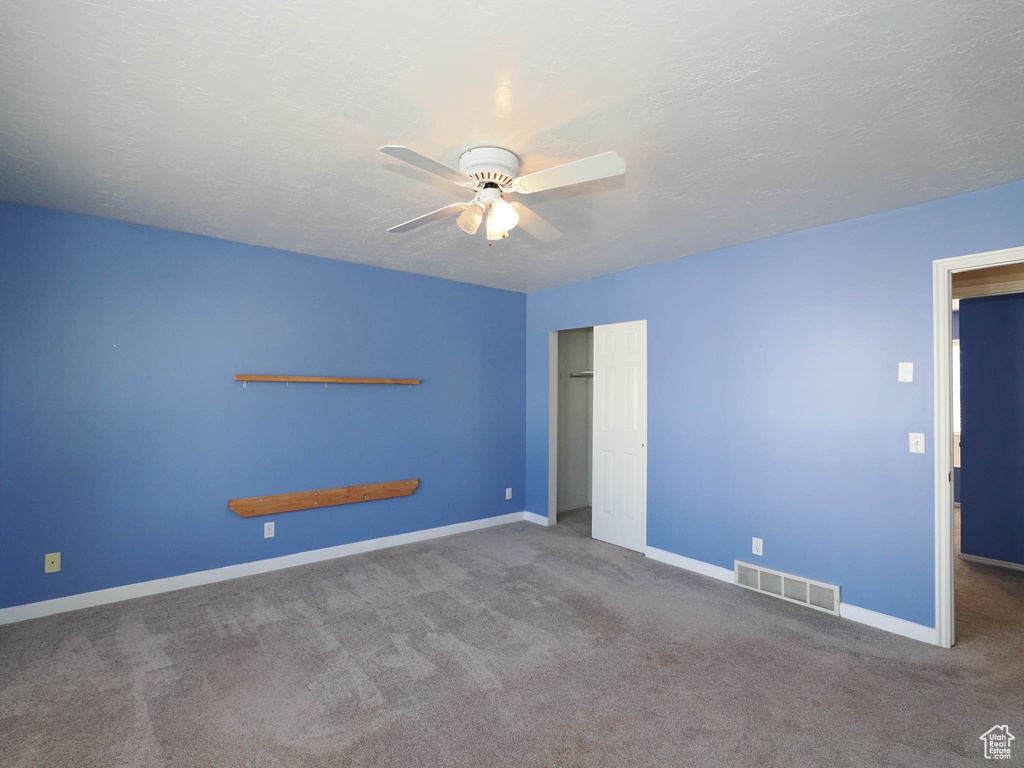Unfurnished bedroom with carpet floors, baseboards, a closet, a ceiling fan, and a textured ceiling