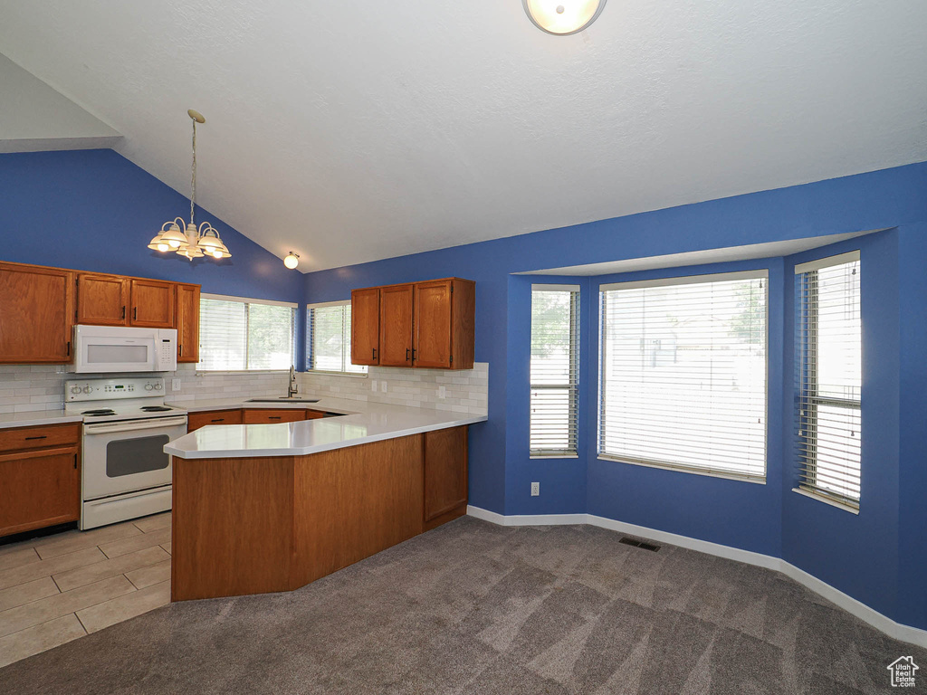 Kitchen with white appliances, a chandelier, light countertops, decorative backsplash, and lofted ceiling