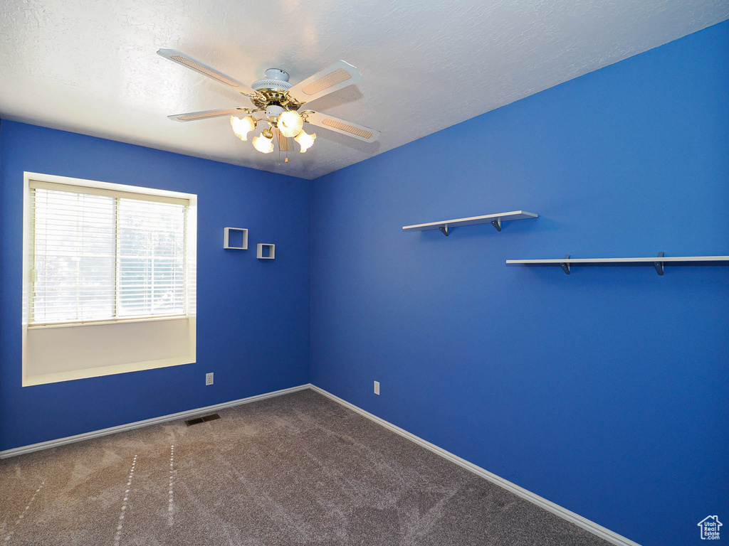 Carpeted spare room with ceiling fan and baseboards