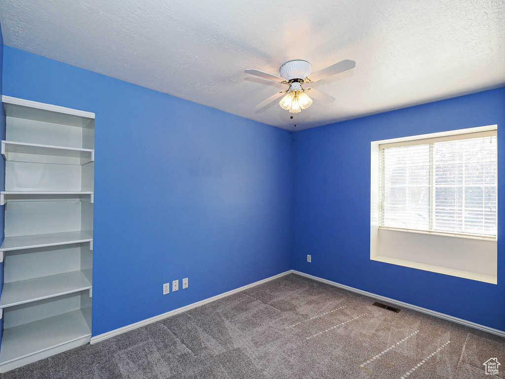 Unfurnished room featuring a ceiling fan, carpet flooring, baseboards, and a textured ceiling