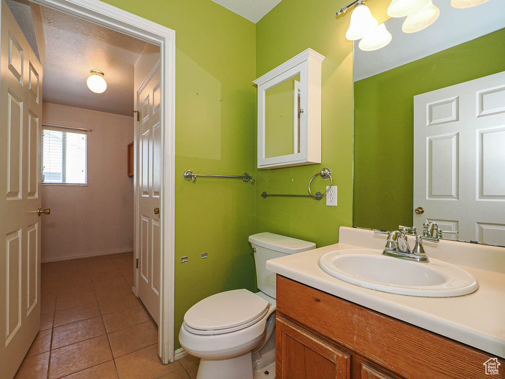 Bathroom with vanity, toilet, tile patterned floors, and baseboards