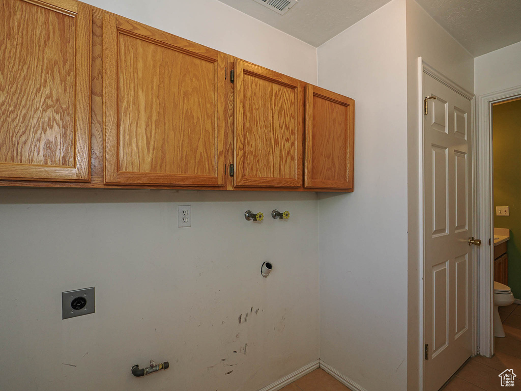 Washroom featuring electric dryer hookup, cabinet space, gas dryer hookup, washer hookup, and tile patterned flooring