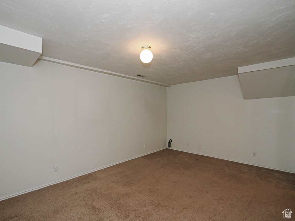 Carpeted spare room featuring baseboards