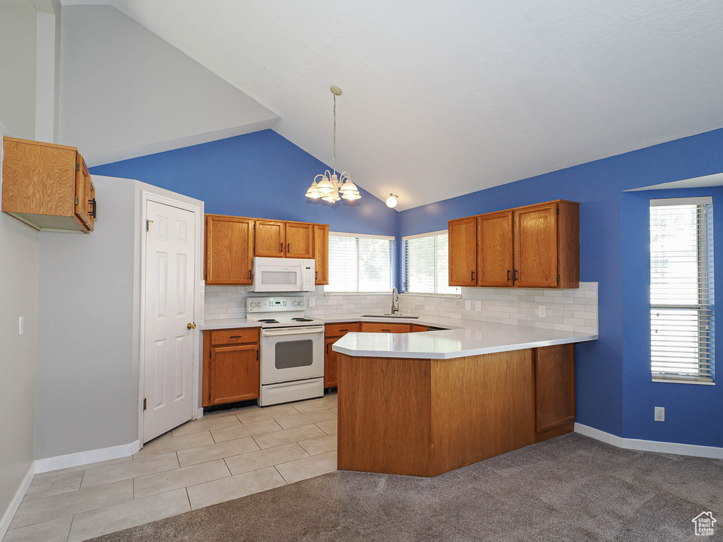 Kitchen featuring white appliances, a sink, a peninsula, brown cabinets, and light countertops