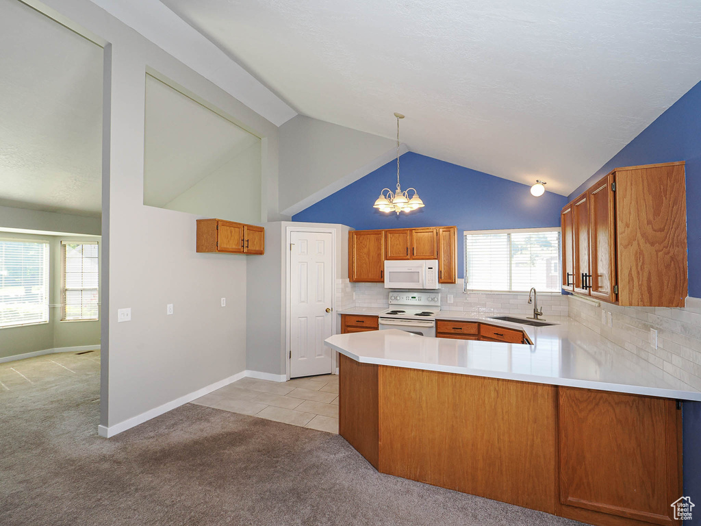 Kitchen with white appliances, a sink, light carpet, a chandelier, and a peninsula