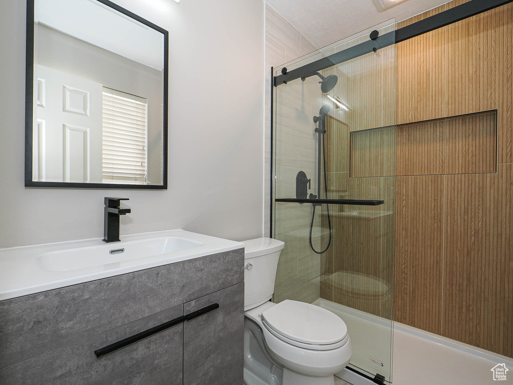 Bathroom with toilet, a tile shower, and vanity