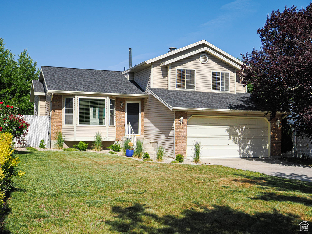 Tri-level home featuring brick siding, an attached garage, roof with shingles, and concrete driveway